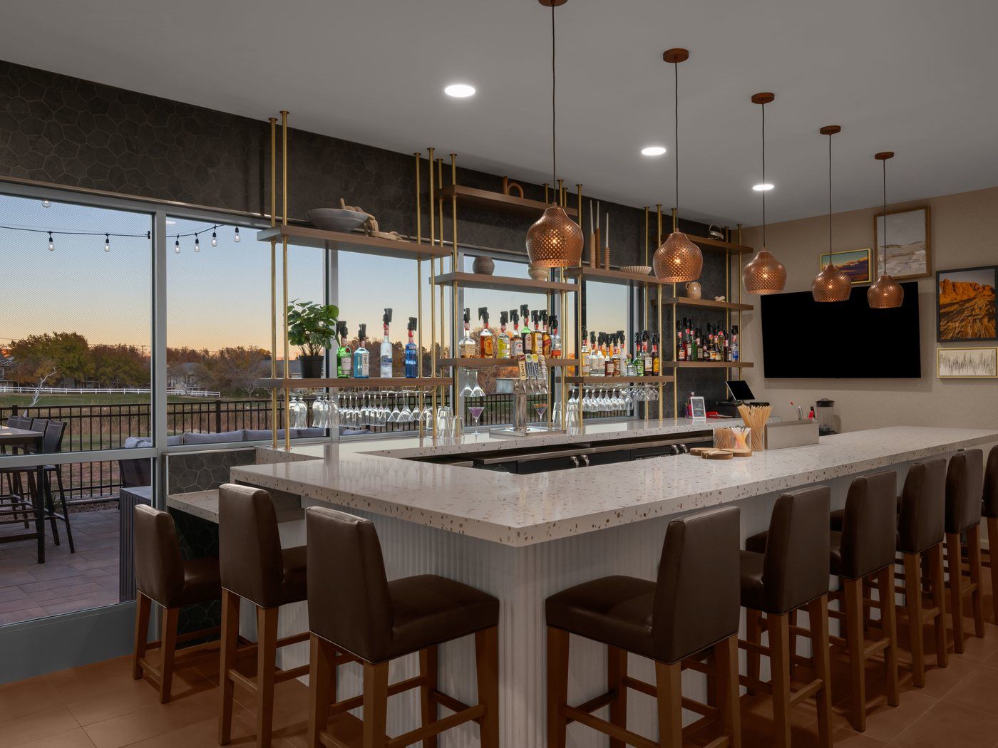 The full bar at Back Nine Bistro & Bar, with bar seating and windows looking out toward the golf course at sunset